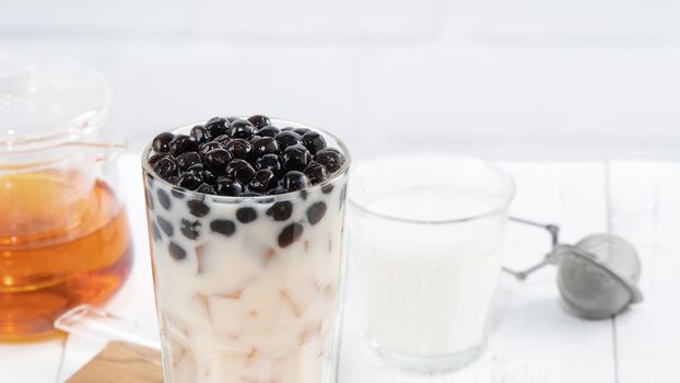 Bubble milk tea with tapioca pearl topping, famous Taiwanese drink on white wooden table background in drinking glass, close up, copy space