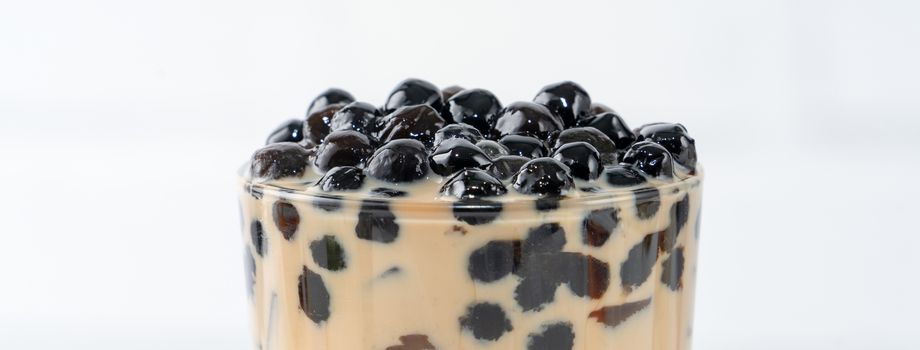 Bubble milk tea with tapioca pearl topping, famous Taiwanese drink on white wooden table background in drinking glass, close up, copy space