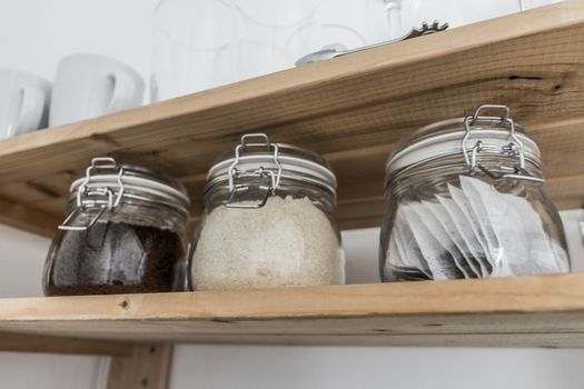 Tea, coffee and sugar in preserving jars on wooden shelf. South Africa.