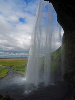 behind the famous icelandic waterfall Seljalandsfoss with the blue sky clouds