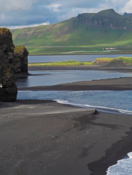 magic iceland landscape with black lava sand and green eroded hills and rocks