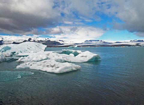 Blue ice block in glacier ice in the Jokulsarlon lagoon in south eastern Iceland blue sky and dark clouds