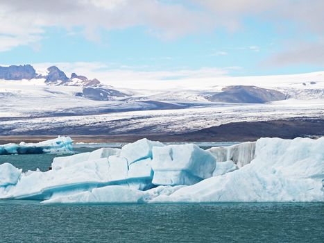 Blue ice block in glacier ice in the Jokulsarlon lagoon in south eastern Iceland with snow tongue and blue sky