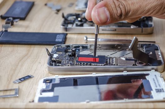 Phone motherboard repairs into the motherboard for smartphone By professional technician on desk.