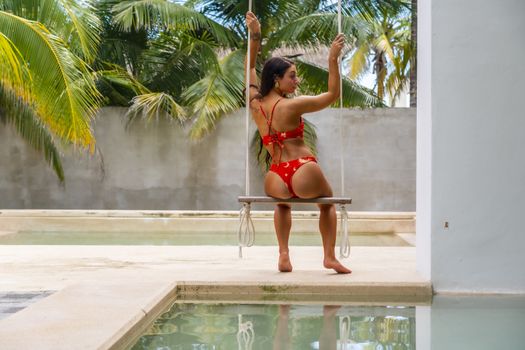 A beautiful brunette bikini model swings by the pool in the Yucatán Peninsula near Merida, Mexico