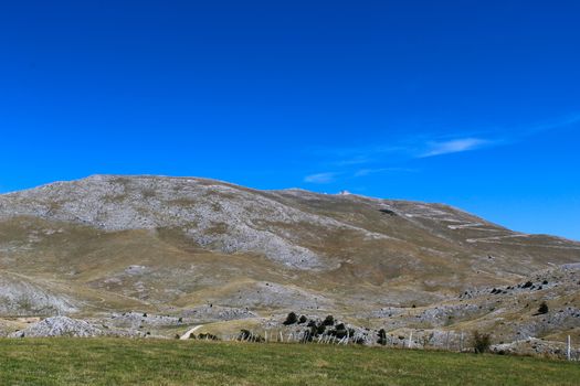 A meadow with a downed fence at the end of the meadow. In the background, mountain desolation. On the way to the mountain Bjelasnica, Bosnia and Herzegovina.