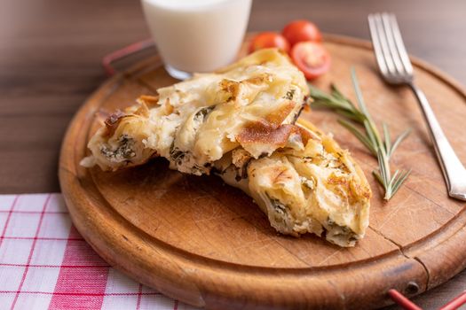 Traditional balkan breakfast - Burek pie with cheese and spinach served on vooden table