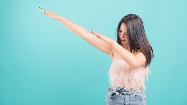 Asian happy portrait beautiful young woman standing smiling exercise Showing DAB dance gesture and looking to side isolated on blue background with copy space for text