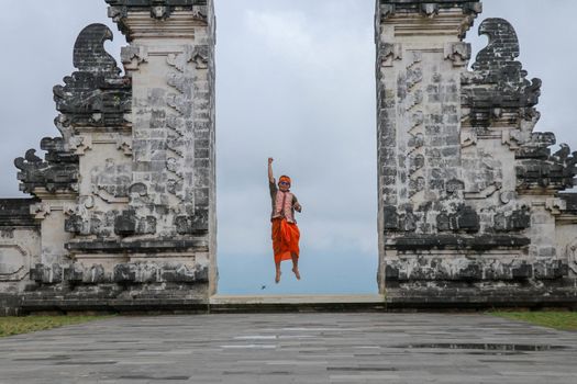 Bali, Indonesia. Traveler man jumping with energy and happiness in the gate of heaven. Lempuyang temple.