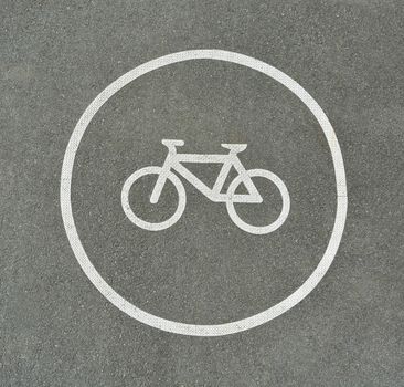 Bicycle sign on asphalt texture marking cyclist lane on a road. Dark corners frame