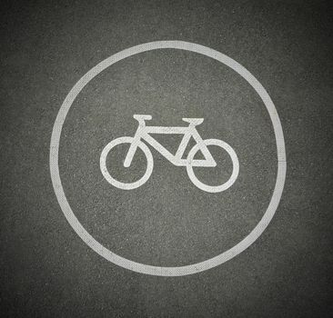 Bicycle sign on asphalt texture marking cyclist lane on a road. Dark corners frame