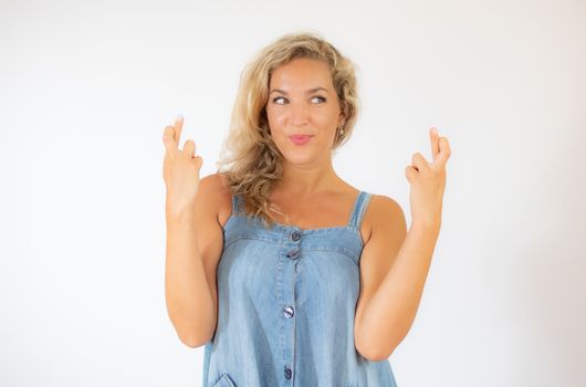 Pretty blonde woman in blue dress smiling and crossing her fingers