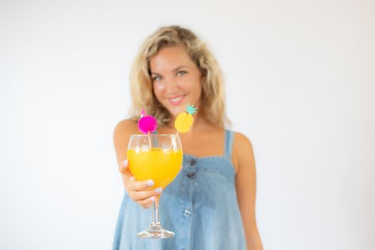 Pretty blonde woman in blue dress smiling with a fruit cocktail