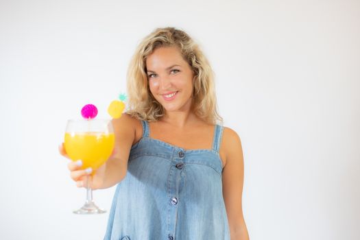 Pretty blonde woman in blue dress smiling with a fruit cocktail