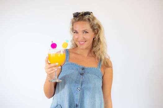 Pretty blonde woman in blue dress smiling with a fruit cocktail