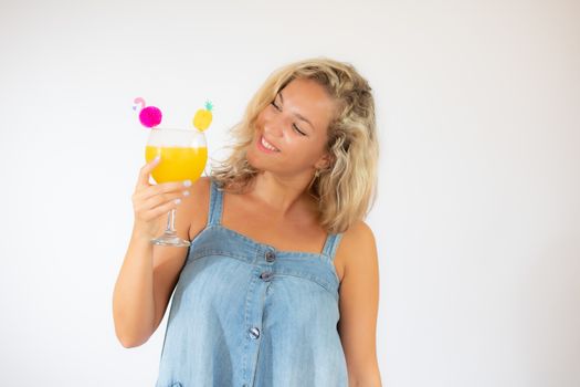 Pretty blonde woman in blue dress smiling with a fruit cocktail