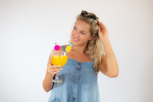 Pretty blonde woman in blue dress smiling with a fruit cocktail on white background