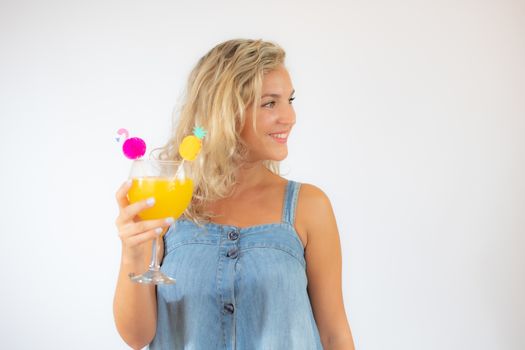 Pretty blonde woman in blue dress smiling with a fruit cocktail