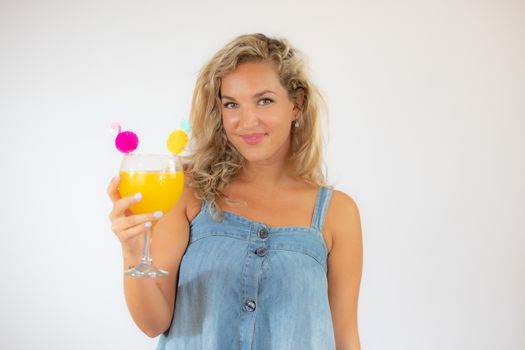 Pretty blonde woman in blue dress smiling with a fruit cocktail