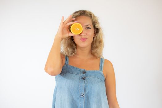Pretty blonde woman in blue dress smiling with an orange in the eye