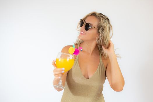 Pretty smiling blonde woman with sunglasses in golden swimsuit with a fruit cocktail