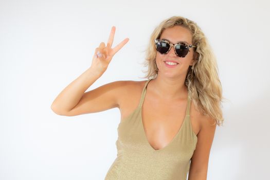 Pretty smiling blonde woman with sunglasses in golden swimsuit