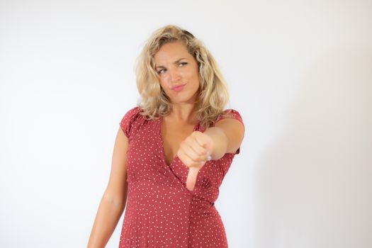 Beautiful blonde woman in a red dress with finger down gesture