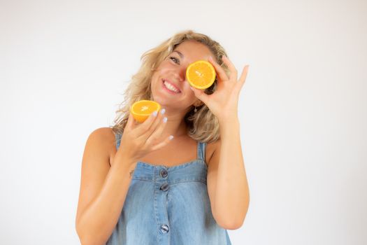 Pretty blonde woman in blue dress smiling with an orange in the eye