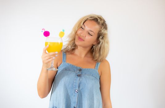 Pretty blonde woman in blue dress smiling with a fruit cocktail