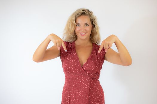 Beautiful smiling blonde woman in a red dress pointing something