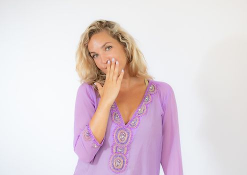 Pretty blonde woman in lila caftan amazed on white background