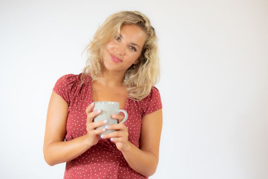 Pretty blonde woman in red dress with a cup of coffee