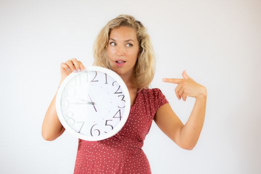 Pretty blonde woman in red dress showing a big clock