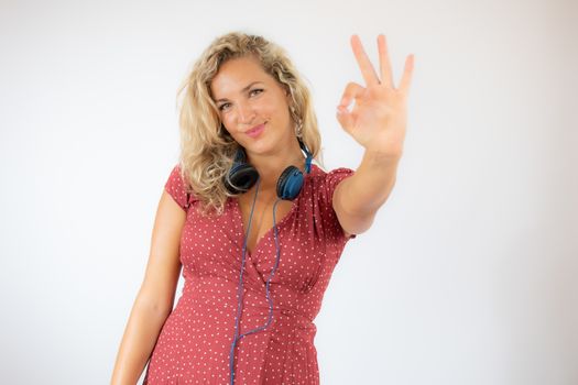 Pretty smiling blonde woman in red dress with headphones