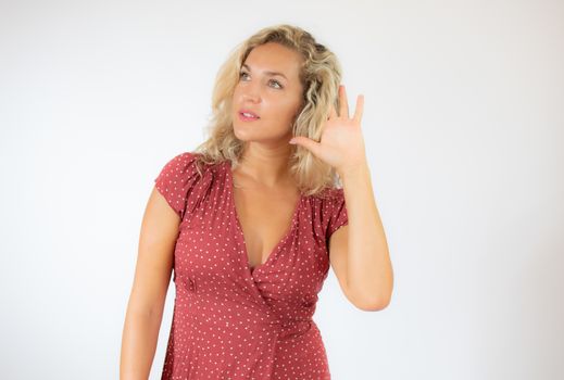 Pretty blonde woman in red dress making listening gesture