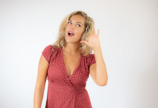 Pretty blonde woman in red dress making listening gesture