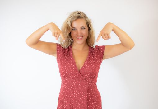 Beautiful smiling blonde woman in a red dress pointing something