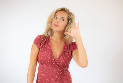 Pretty blonde woman in red dress making listening gesture