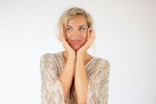 Smiling pretty blonde woman in a party dress gesturing on white background