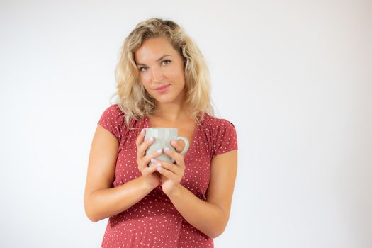 Pretty blonde woman in red dress with a cup of coffee