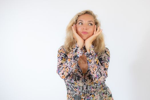 Pretty blonde woman in a flowery dress gesturing on white background