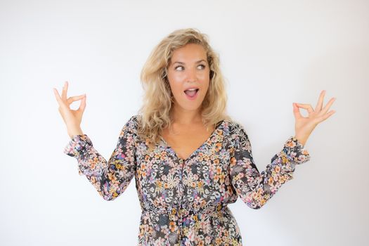 Pretty blonde woman in a flowery dress gesturing on white background