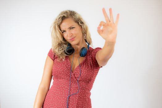 Pretty smiling blonde woman in red dress with headphones