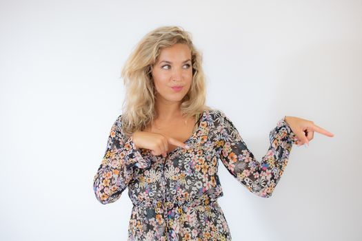 Pretty blonde woman in a flowery dress gesturing on white background