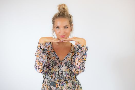 Pretty blonde woman in a flowery dress gesturing on white background