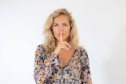 Pretty blonde woman in a flowery dress gesturing on white background