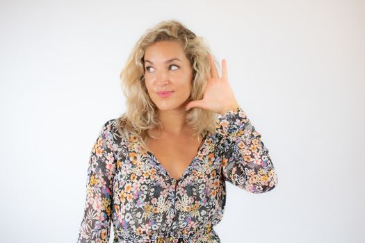 Pretty blonde woman in a flowery dress gesturing on white background