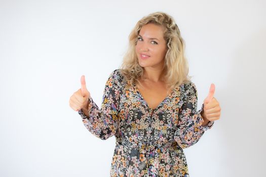 Pretty blonde woman in a flowery dress gesturing on white background