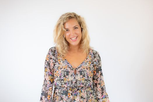 Pretty blonde woman in a flowery dress gesturing on white background