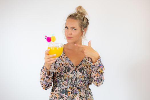 Pretty blonde woman in a flowery dress with a cocktail on white background